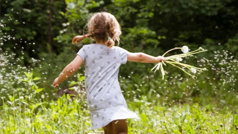 Little girl running on a field with flowers